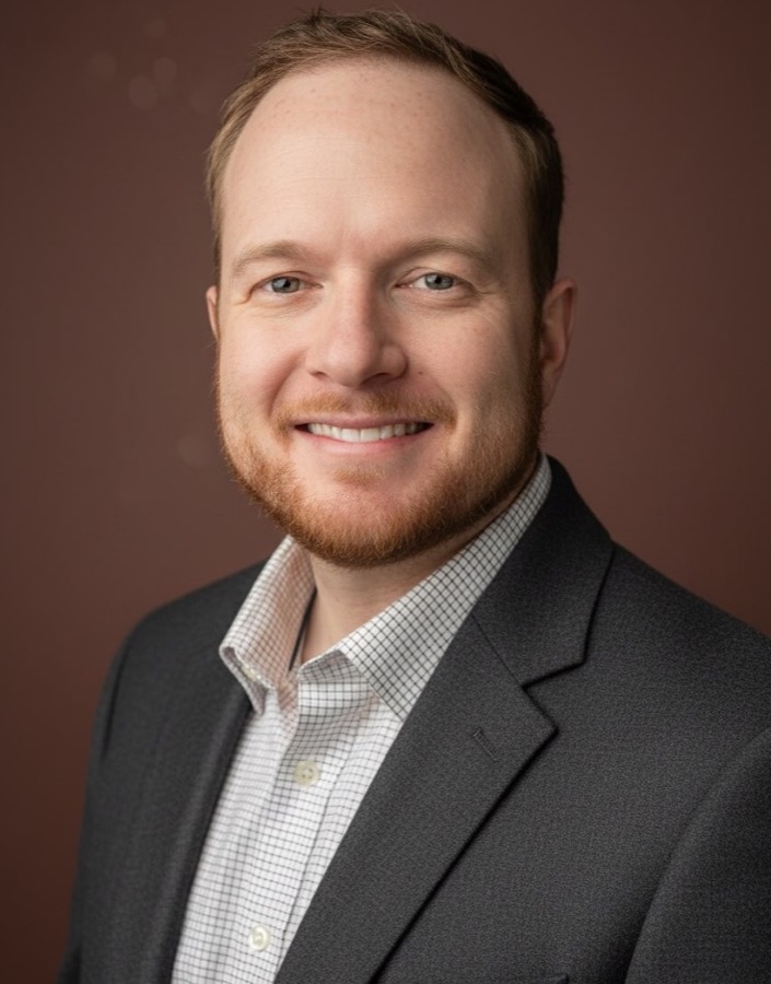 Black-and-white portrait of Bryan Leeper, smiling, wearing a dark jacket.